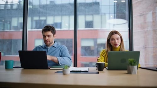 Man and Woman Working at Laptops in Office