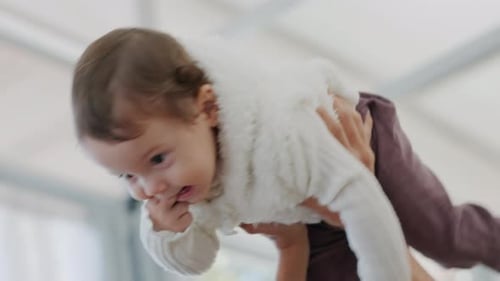 Parent Holding Smiling Baby Aloft in Playful Moment