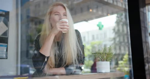 Mixed Race Blond Woman Drinking Coffee Sitting Indoor in Urban City Cafe