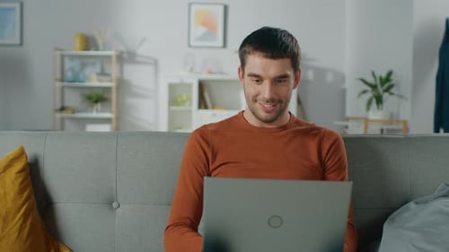 Man Uses Laptop on Sofa in Bright Living Room