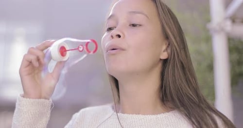 Girl Blowing Bubbles Outdoors in the Daytime