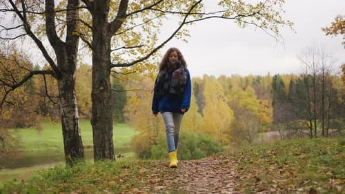 Woman Walking in Autumn Park Wearing Yellow Rubber Boots