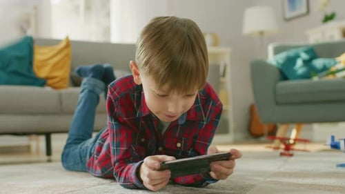 Boy Lies on Rug Playing with Phone