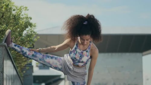 Young Woman Stretching Leg Muscles on Urban Street