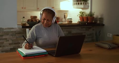 Woman Works at Table with Laptop and Notebook
