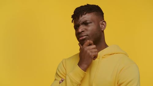 Thoughtful Man Ponders on Yellow Backdrop