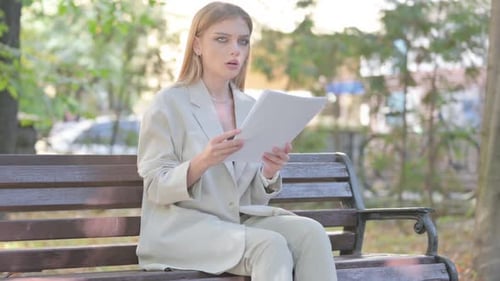 Woman Reads Documents on Bench in the Park