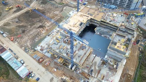 Survol aérien d'un site de développement de nouvelles constructions avec des grues à haute tour qui construisent des biens immobiliers.