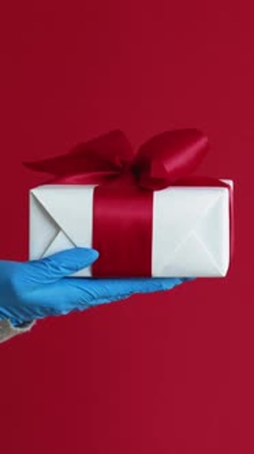 Gloved Hand Holds Birthday Present on Red