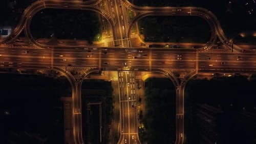 Vista aérea de automóviles que se mueven a lo largo de un intercambiador de autopistas brillantemente iluminado por la noche en China
