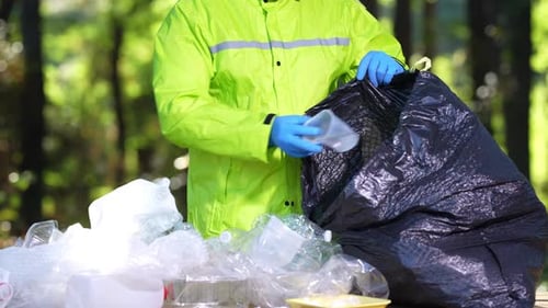 Person Sorting Recyclable Plastic Into Garbage Bag Outdoors