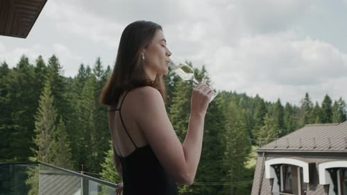 Girl In An Evening Dress Drinks Champagne On Hotel Balcony