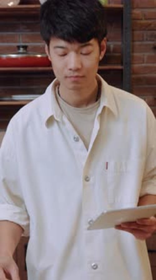 Young Adult Follows Cooking Recipe on Tablet