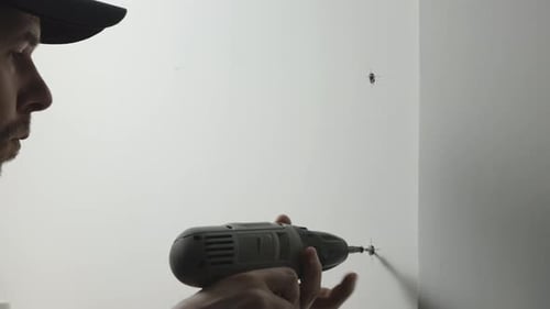Man Drills Screws into Wall