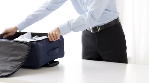 Man packs clothes into blue luggage bag