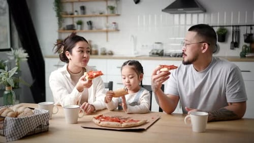 Happy Family Eating Pizza Together in Bright Kitchen