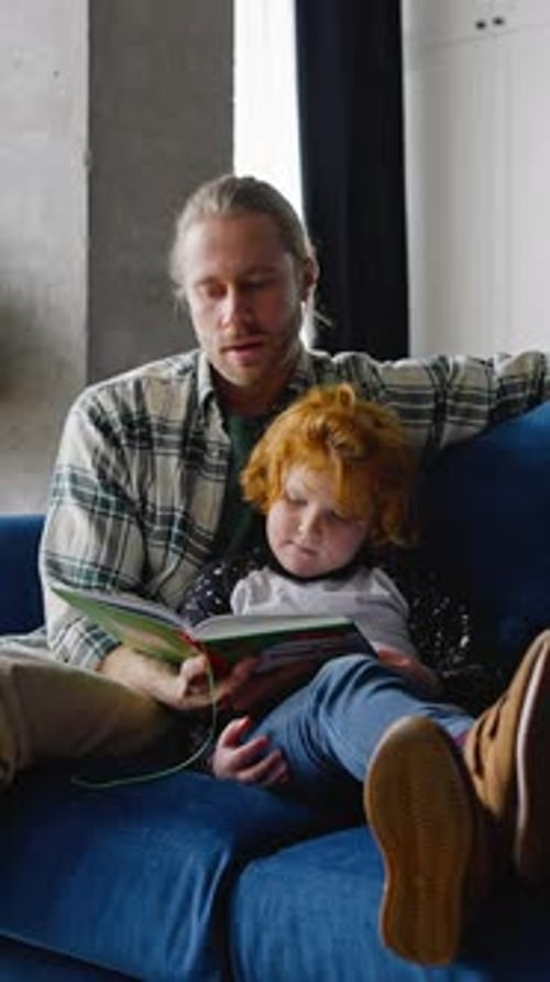 Father and Child Reading a Book on Couch