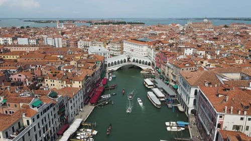 Aerial shot of boats moving under the renowned Ponte di Rialto in venice italy
