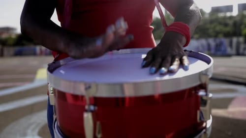 Red sport football fan celebrating playing drums at stadium tribune. Soccer spectator watching match