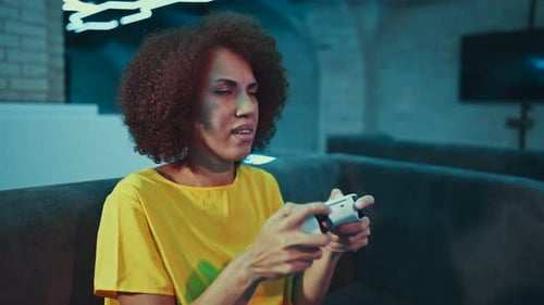 A Young Woman Plays a Console in a Room with Neon Lights