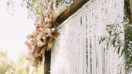 Closeup Floral Cluster on Wedding Arch Post Macrame Fringe and Pampas Accents Pale Pink Roses