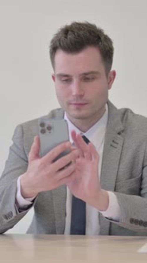 Young Businessman Browsing Internet on Smartphone in Office, vertical video