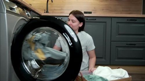 Woman Loads Clothes into Washing Machine at Home