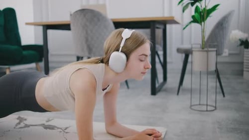Woman Doing Plank Exercise Wearing Wireless Headphones