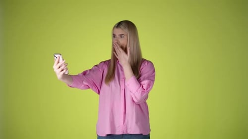 Cucasian woman looks at her cellphone amazed and surprised mobile studio blonde girl shot with techn