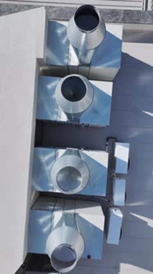 Vertical Video Aerial View of a Building Roof with Large Industrial Fans and Exhaust Systems