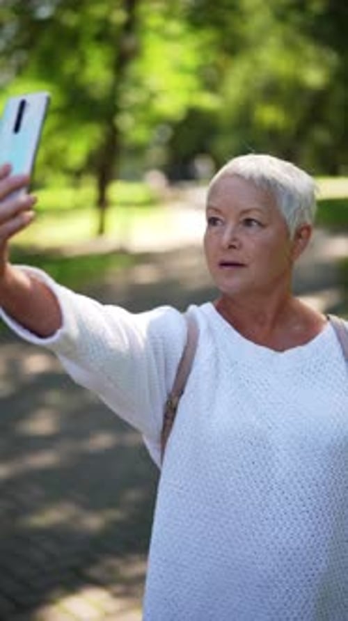 Senior Woman Taking Selfie in Urban Green Park