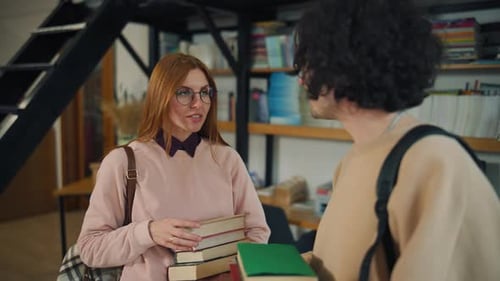 Groupe de personnes parlant dans une bibliothèque tout en tenant des livres et en discutant de matériel de lecture dans un endroit calme