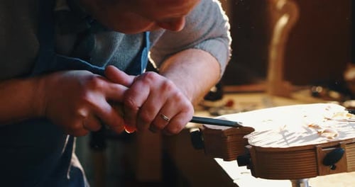 Slow motion of master artisan luthier working on creation of handmade violin in a workshop. Shot