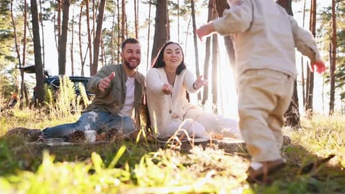 Boy walking to his parents. Family of father, mother and little son is outdoors in the forest