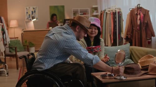 Wheelchair User with Friend Shopping for Vintage Accessories in Secondhand Store