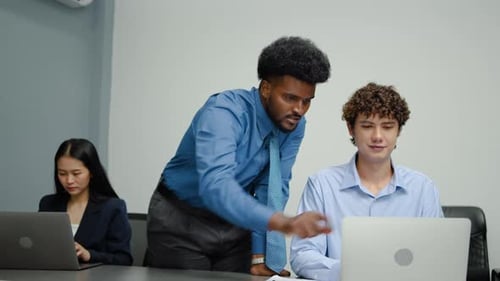 Kaukasische und afroamerikanische Männer arbeiten zusammen an einem Laptop, mit einer asiatischen Kollegin