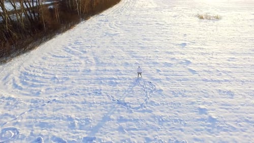 Man Walking Alone in Snow Covered Field