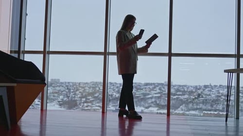 Young Adult Woman Uses Tablet and Phone in Office