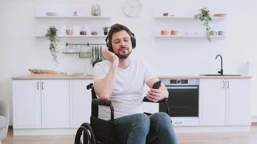 Man in Wheelchair Listening to Music at Home