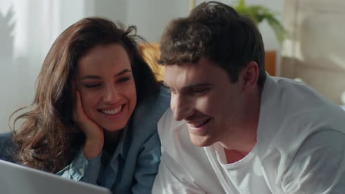 Smiling Young Couple Looking at Laptop Screen Indoors