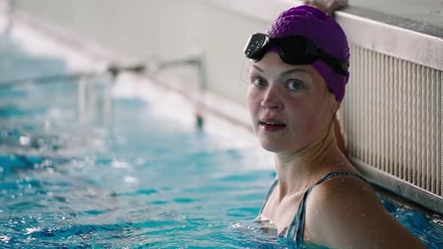 Woman Swimmer Resting at Edge of Indoor Pool