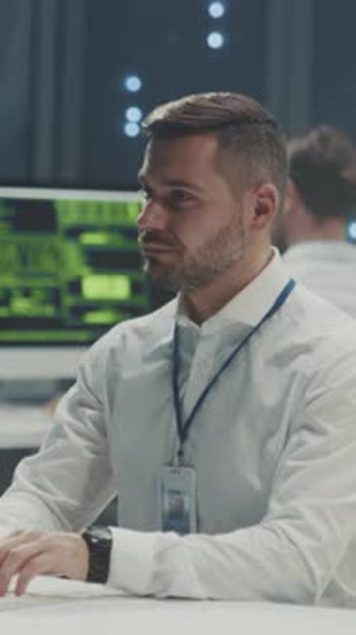 Desk Security Analyst with Serious Expression Analyst at Control Station Attentively Watches Server