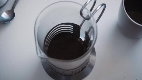 Static close up shot of coffee and boiling water being poured into a french press.
