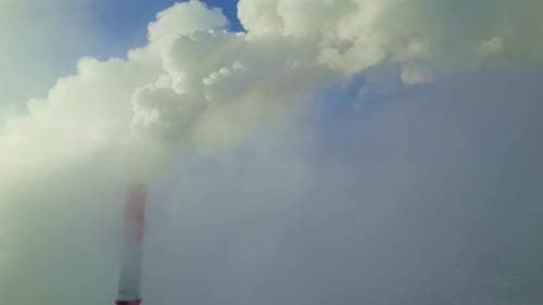Smoke Billows From Industrial Chimney Against Clear Blue Sky at Midday