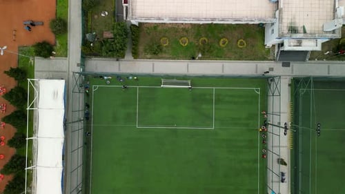 Drone shot of a football field with boy playing a game