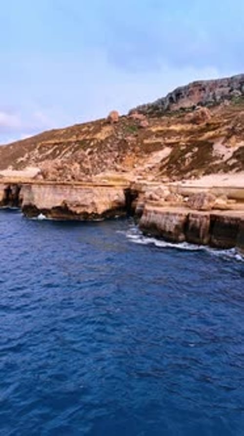 Flying away from the bare rocks at the coast of Malta. Cliffs at the shore of the Mediterranean Sea