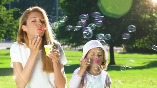 Mother and Daughter Blowing Bubbles at Park