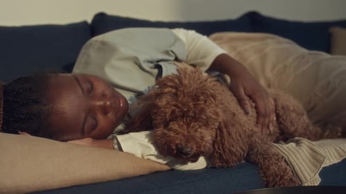 Black Nurse Taking Nap on Couch and Petting Dog
