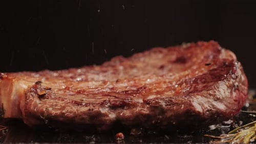 Fresh Marbled Beef with Pepper Salt and Rosemary Closeup Macro Cooking Juicy Steak on Grill with Oil