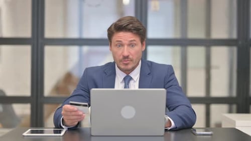 Worried Businessman with Credit Card and Laptop
